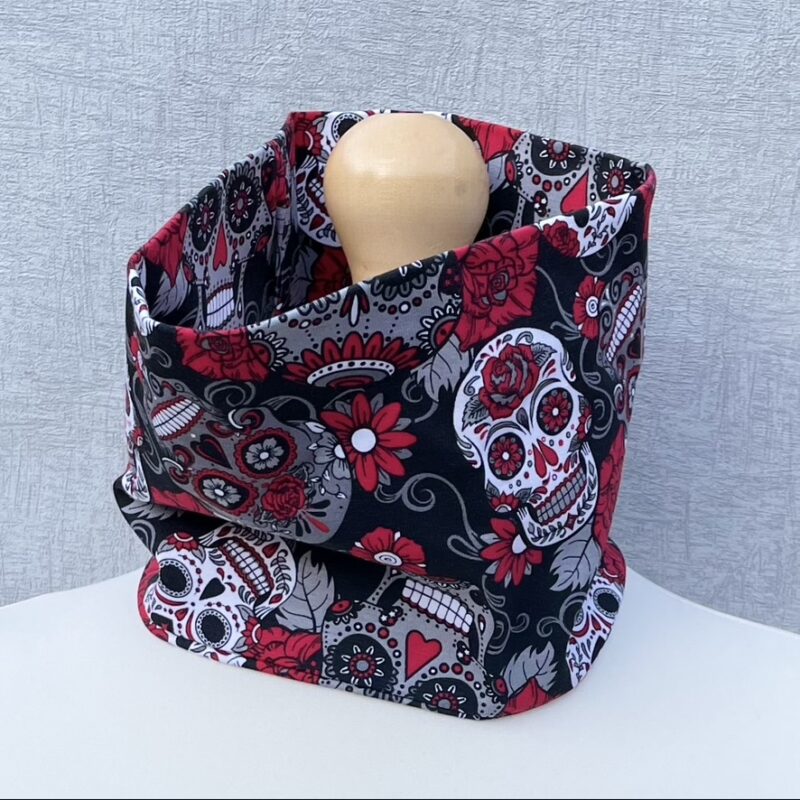 Neck Gaiter in Sugar Skulls jersey in grey and white with red detailing. Pictured on a mannequin with pale shoulders and a pale wood topper.