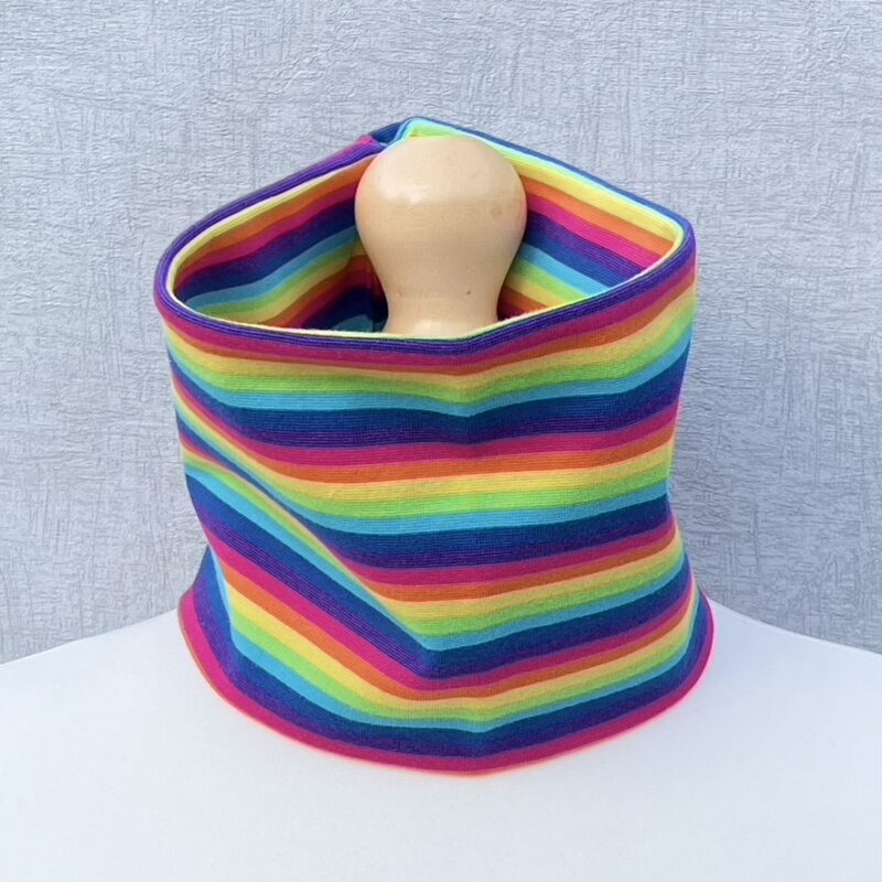 Neck Gaiter in Rainbow Stripe Jersey sitting on a mannequin with a cream body and pale wooden top.