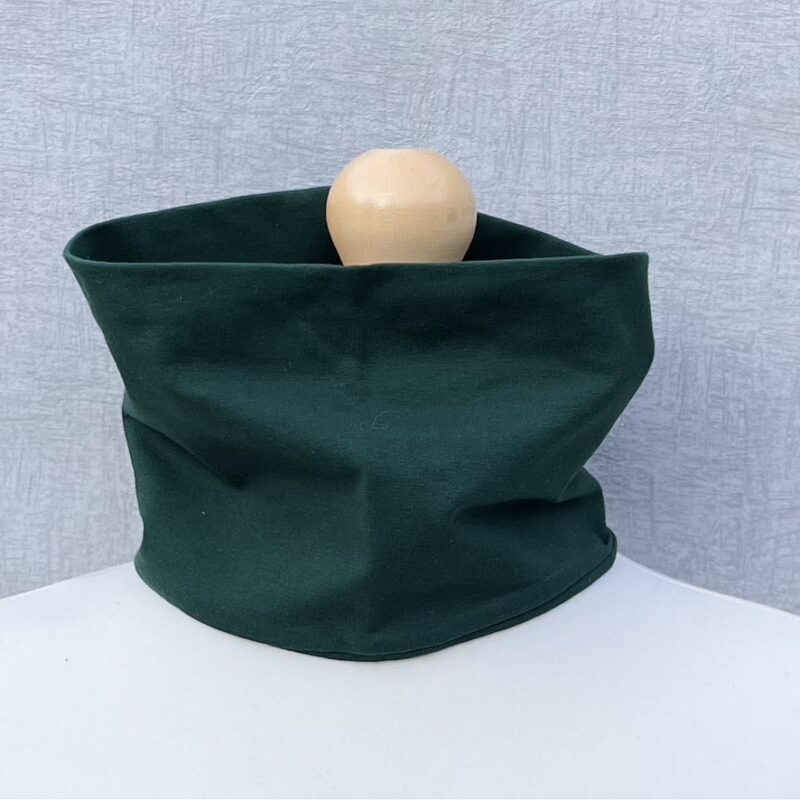 Jersey Neck Gaiter in Forest Green Jersey. Plain, no pattern. On a mannequin with pale shoulders and a wooden topper. Light grey background.