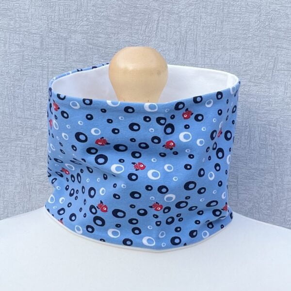 Jersey Neck Gaiter with closely spaced black bubbles with little red fish at a short distance apart within the bubbles and a blue background. On a mannequin with pale shoulders and a wooden topper. Light grey background.